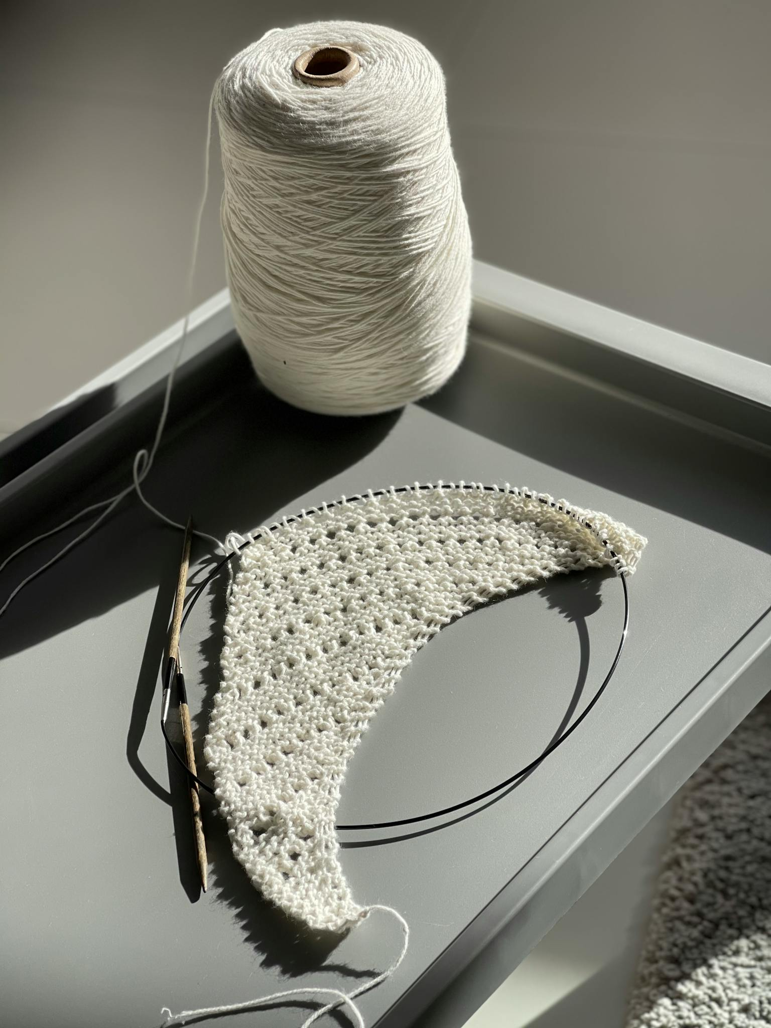 A detailed view of crochet work in progress using white yarn and a crochet hook.